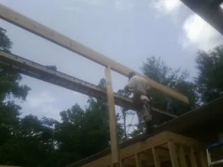 Carpenter setting a ridge beam over a new addition frame — Ice Dam Removal by Roofing Brothers in Haines