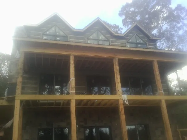 Dormers and porch framing on a large log home under construction — Roof Coating work by our crew in Haines