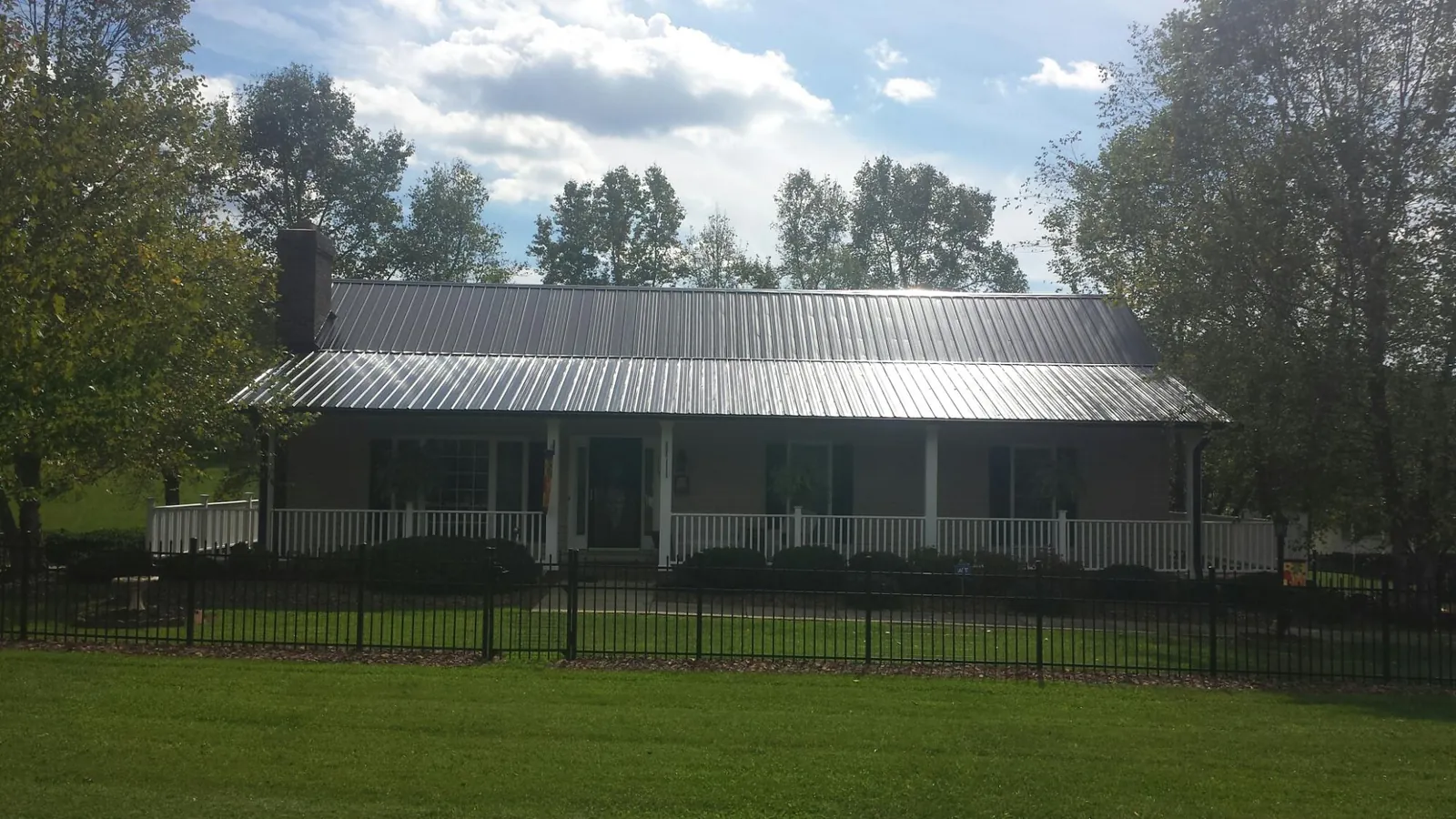 Gray metal roof on a brick ranch with a full width front porch — Gutter Guard Installation work by our crew in Haines