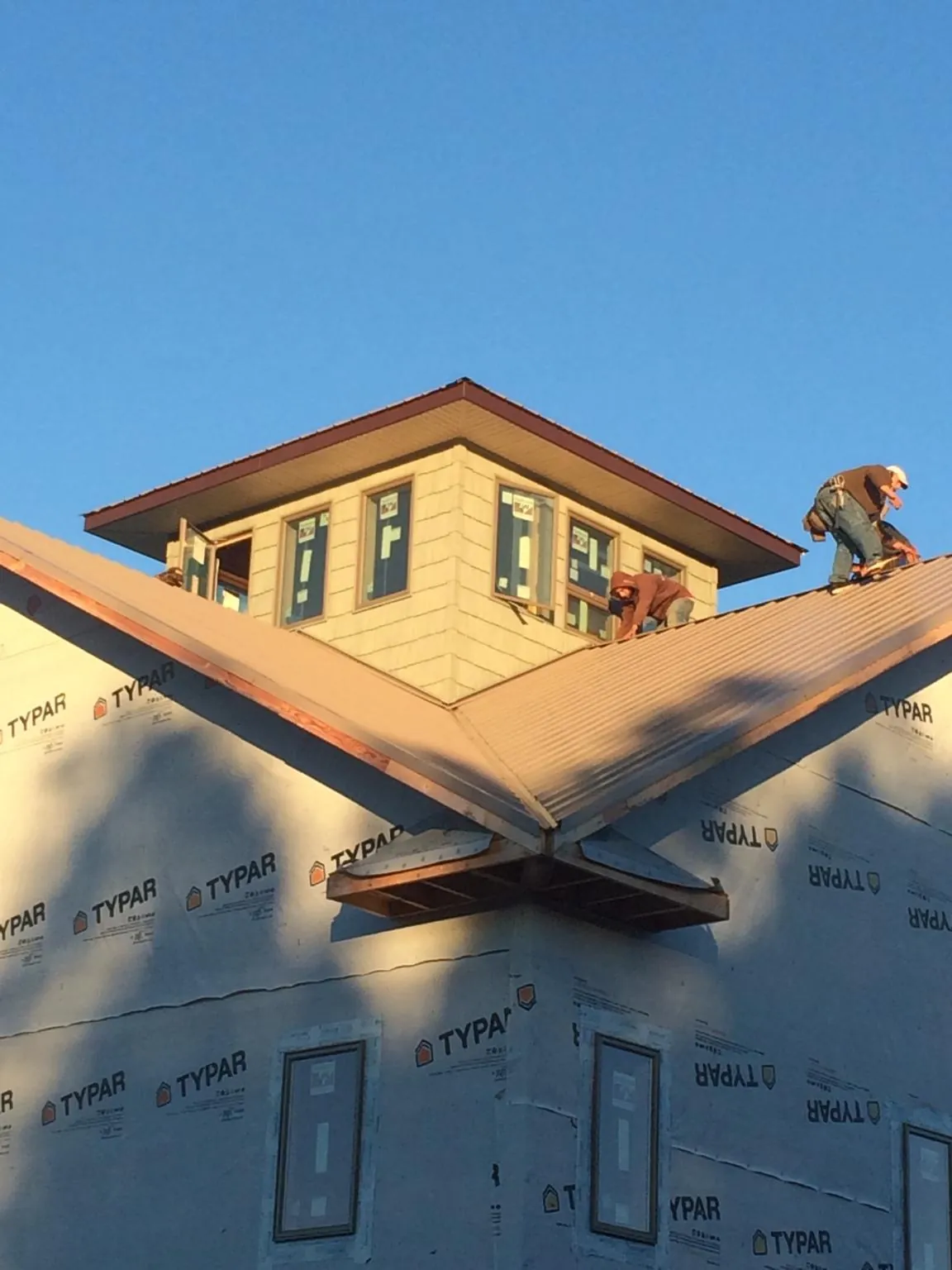 Roofers working around a rooftop cupola on a new metal roof at sunset — Roof Waterproofing in Haines by Roofing Brothers